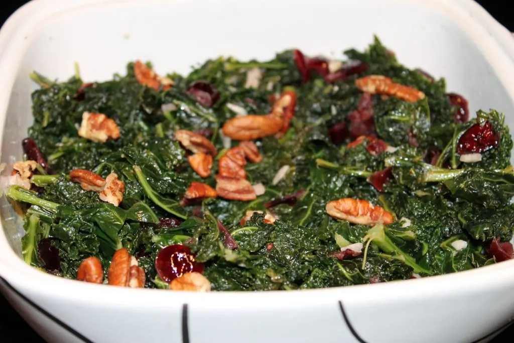 Cooked kale with pecans and cranberries in square casserole dish.