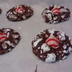 Chocolate crinkle cookies with red and white striped kisses on parchment paper