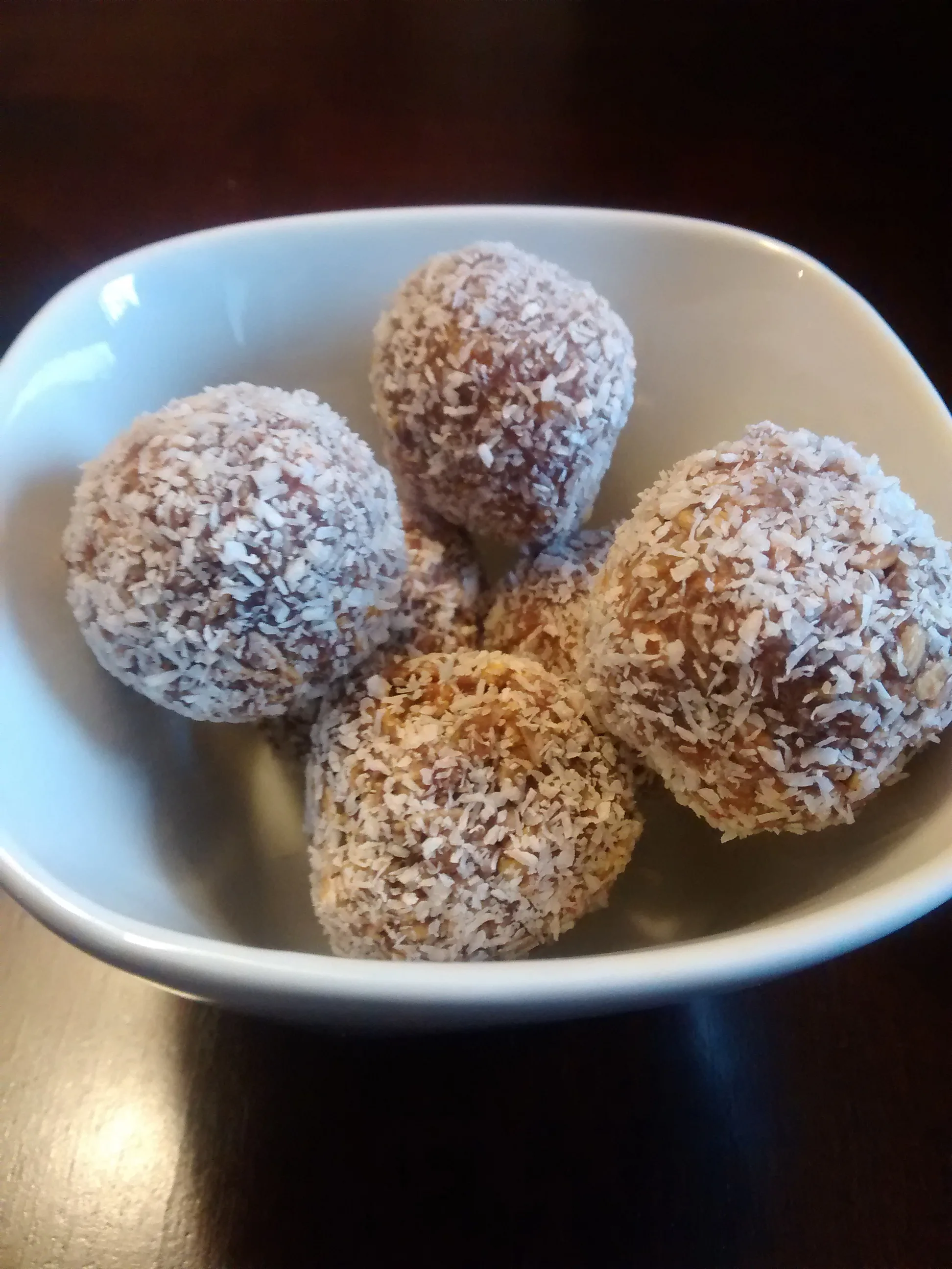 Snowball Cookies rolled in flaked coconut and piled in a white ceramic bowl