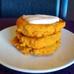 Sweet potato fritters stacked on white plate with aioli spread