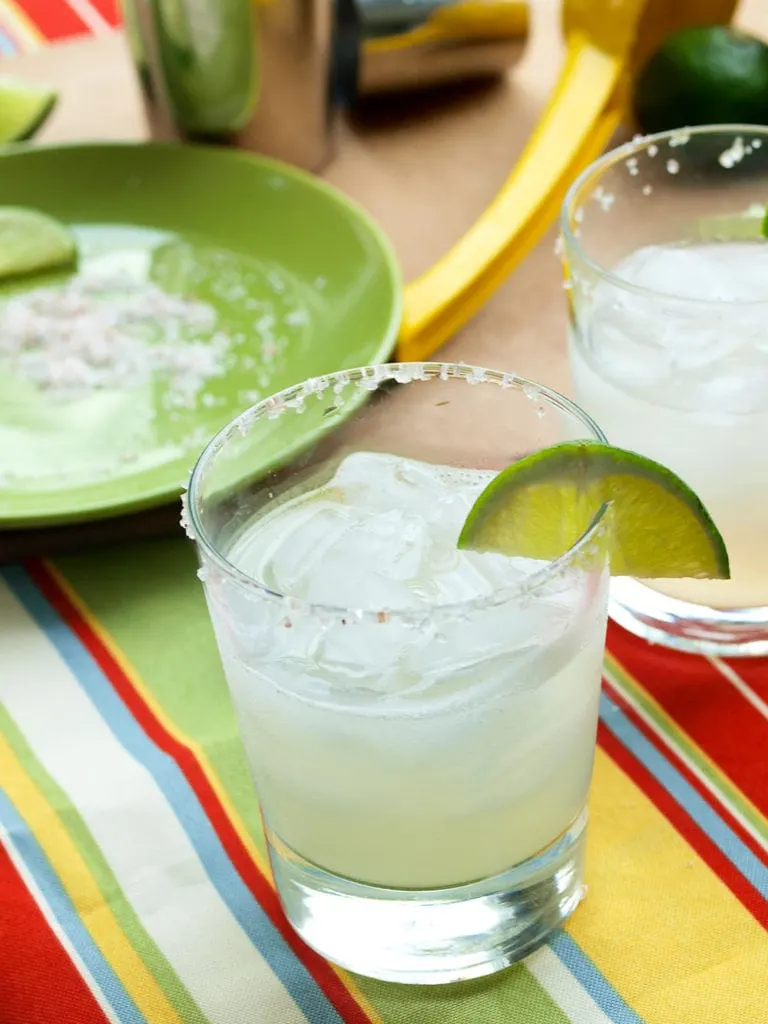Glasses filled with the best margarita dipped in salt and served with fresh lime