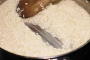 Stirring risotto with wooden spoon in skillet to create creamy consistency