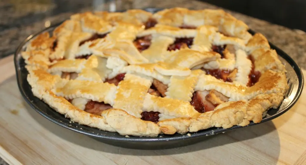 Freshly baked apple pie on wooden cutting board