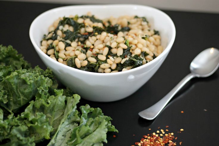White Bean and Kale Salad in white ceramic bowl on black tablecloth.