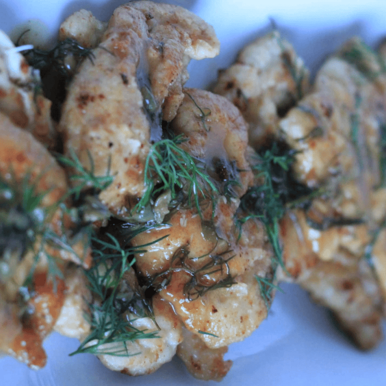 Close up photo of chicken piccata on long white tray.
