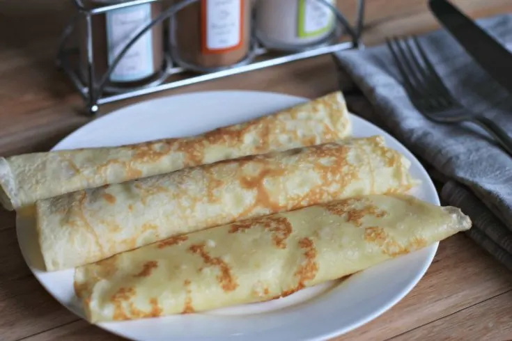 White serving plate with 3 fresh crepes rolled up