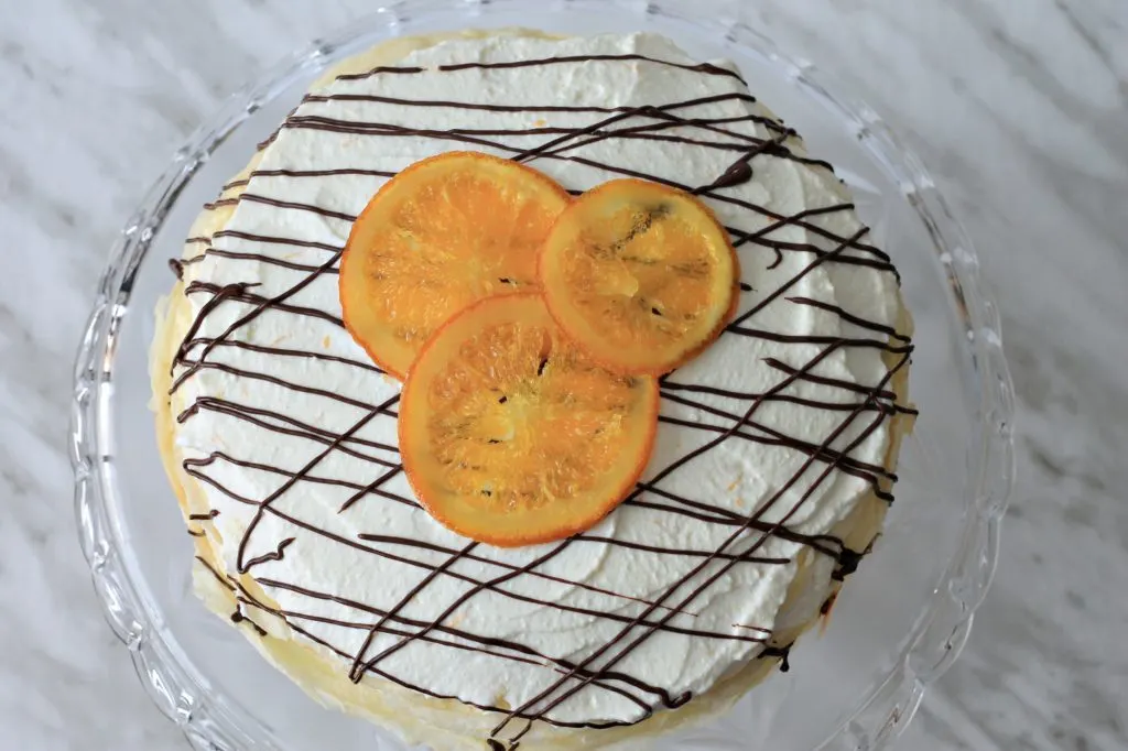 Finished crepe cake with drizzled chocolate and candied oranges