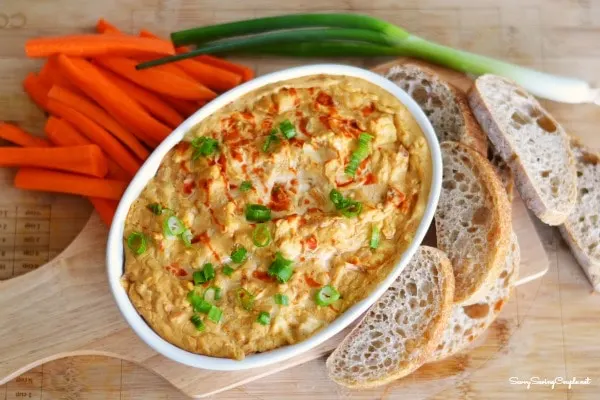 Oval dish with Buffalo Dip surrounded by veggies and bread crisps