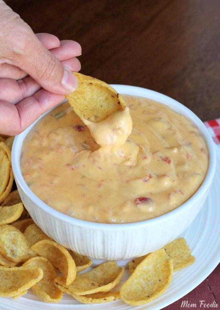 Cheesy Queso Dip in white bowl scooped out with corn chips