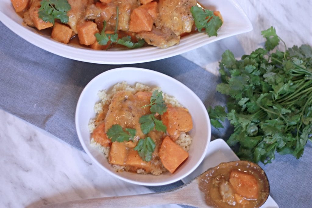 Moroccan Chicken Stew in large white serving bowl with fresh herbs