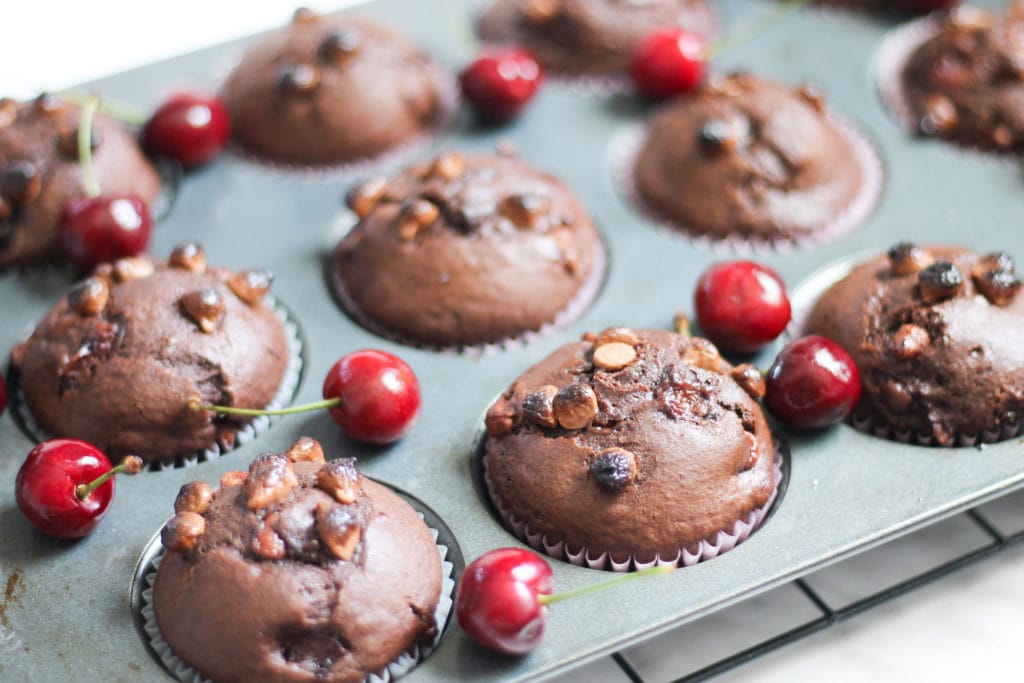 Chocolate Cherry Muffins in muffin tin with scattered cherries