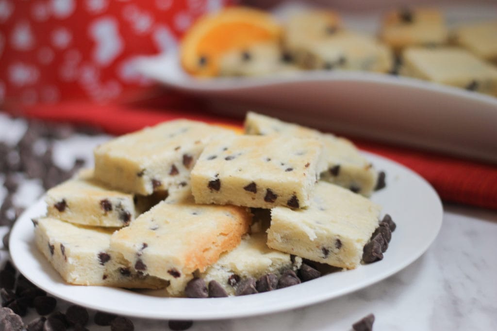 White plate full of delicious shortbread bars surrounded by chocolate chips 