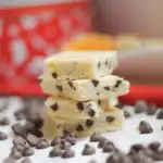 Stacked Chocolate Chip Citrus Shortbread Bars surrounded by scattered chocolate chips and Christmas tins