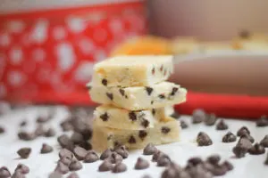 Stacked Chocolate Chip Citrus Shortbread Bars surrounded by scattered chocolate chips and Christmas tins