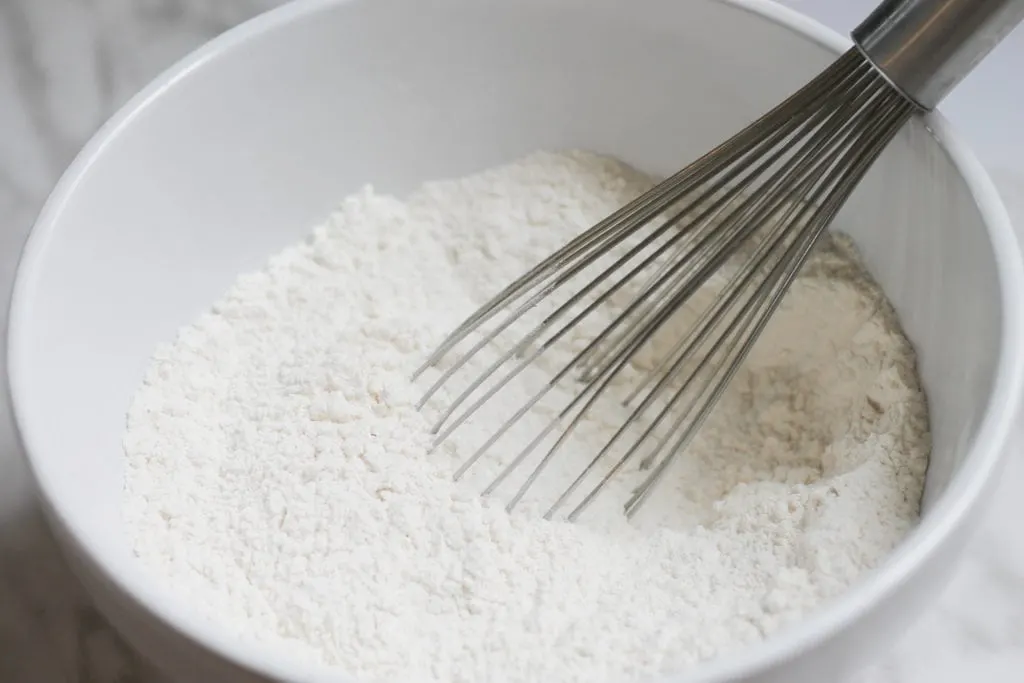 White ceramic bowl with dry ingredients and whisk 