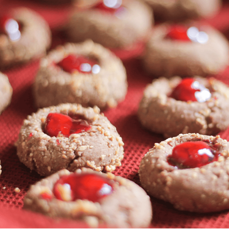 Chocolate cherry thumbprint cookies on red tablecloth.