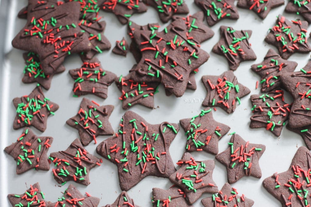 Chocolate Shortbread Cookie stars with festive sprinkles on baking sheet