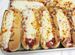 Tray of meatball subs topped with melted cheese