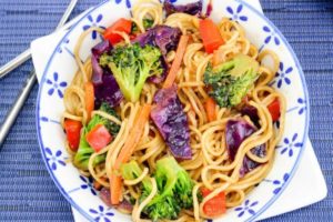 Blue and white bowl filled with vibrant vegetable lo mein