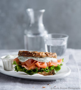 White plate with salmon panini and glass of water