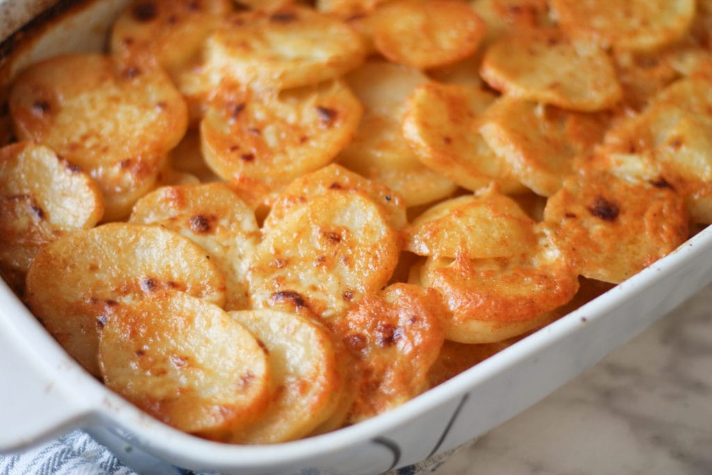 White casserole dish with cooked scalloped potatoes
