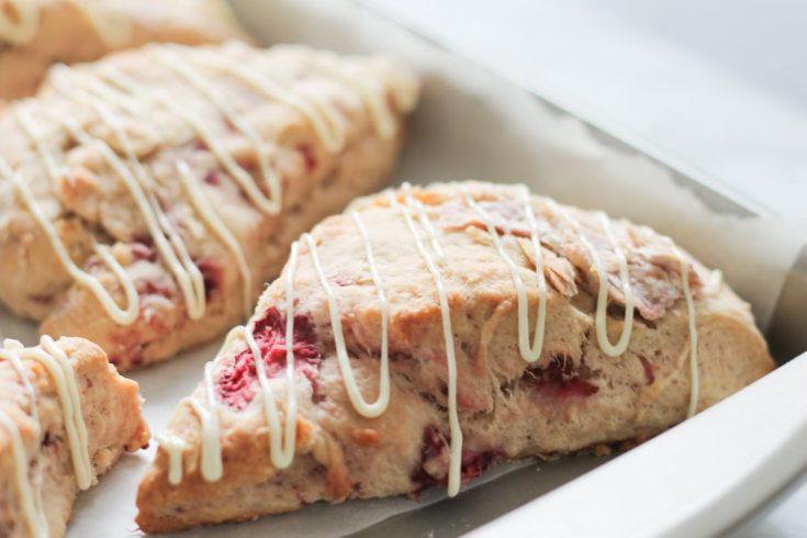 fresh baked strawberry scones with white chocolate drizzle on baking tray