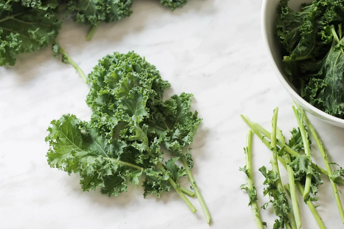 Kale leaves on marble counter top with stems removed