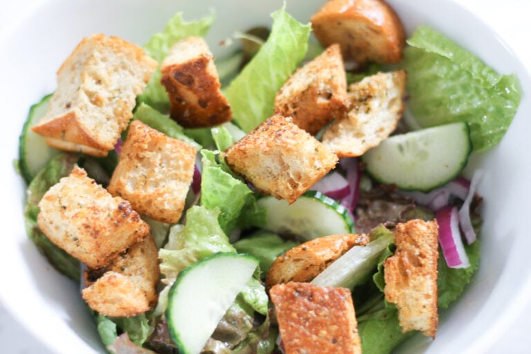 Bowl of green salad topped with croutons.