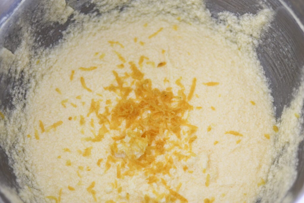 Cake batter in mixing bowl with lemon zest on top.
