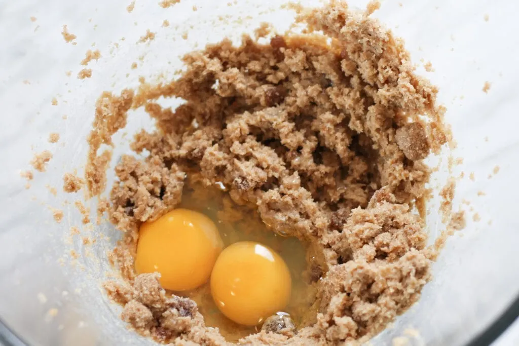 Creamed butter and brown sugar with two eggs in large glass bowl.