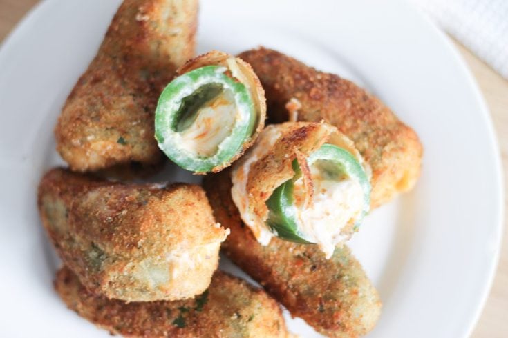 White appetizer plate with cooked jalapeno poppers.