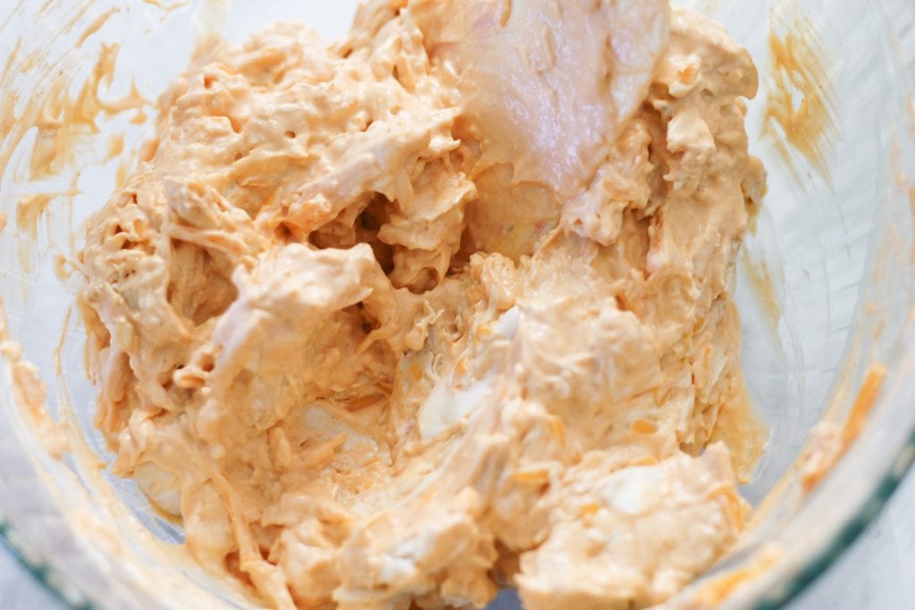 Mixing of buffalo dip in clear bowl.